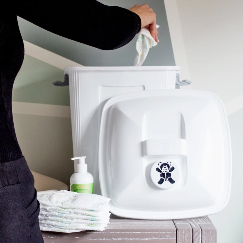 white plastic diaper collection container with woman putting used diaper into bin