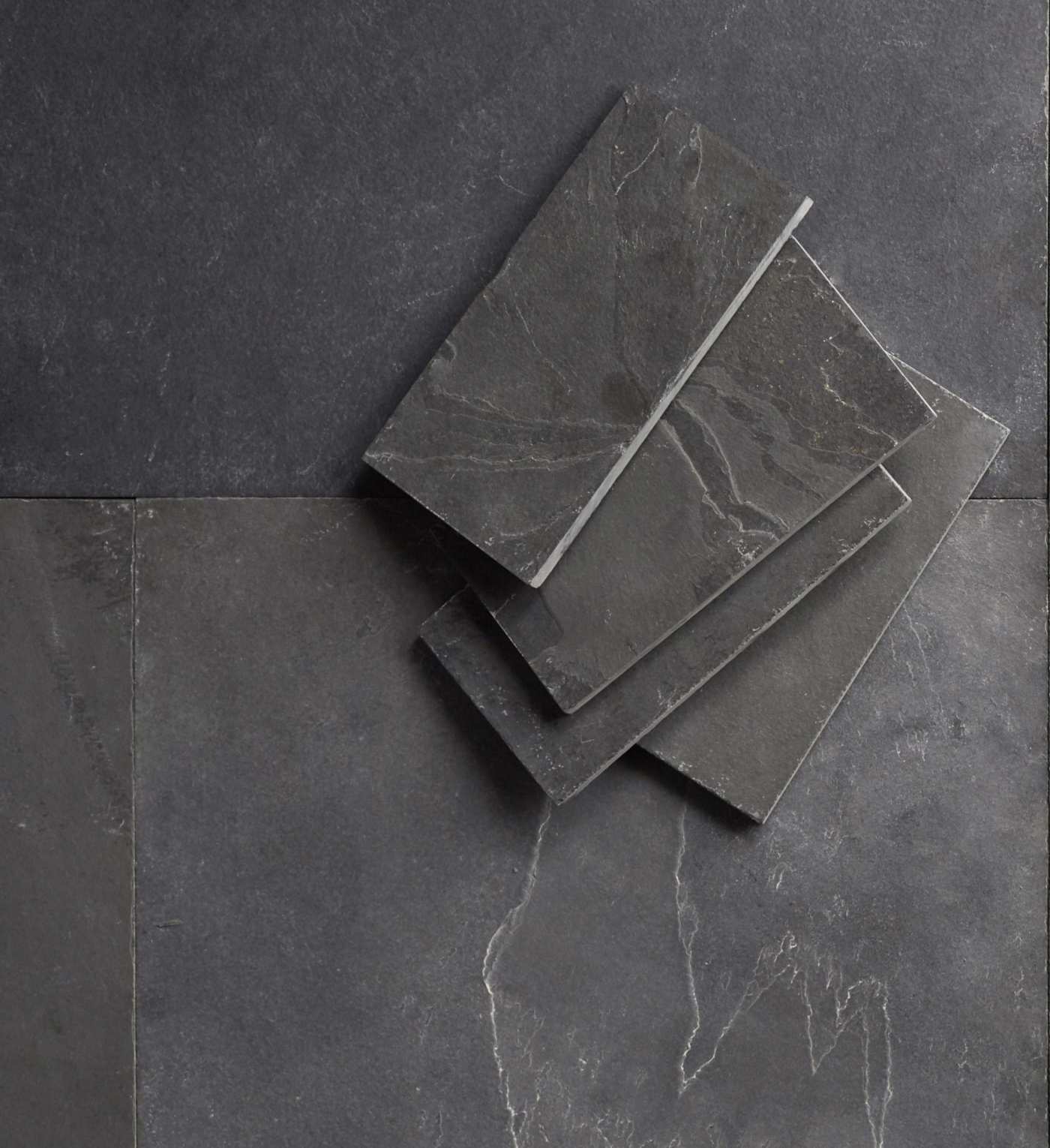 grey slate tiles stacked on top of each other on a dark grey surface.