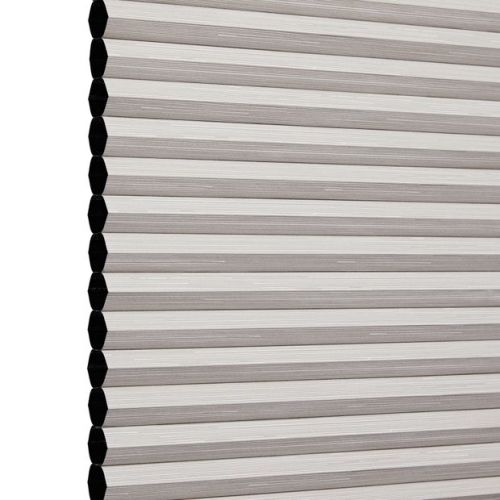 Honeycomb cellular blind, lowered and fully closed with visible hexagonal cell ends and beige horizontal pleats, blocking light; photographed against a plain white studio background.