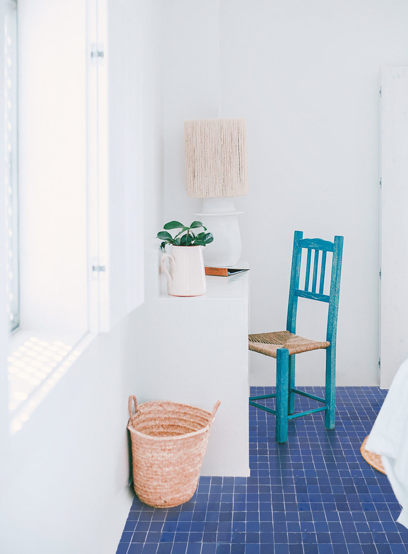 a blue tiled bedroom with a chair and a potted plant.