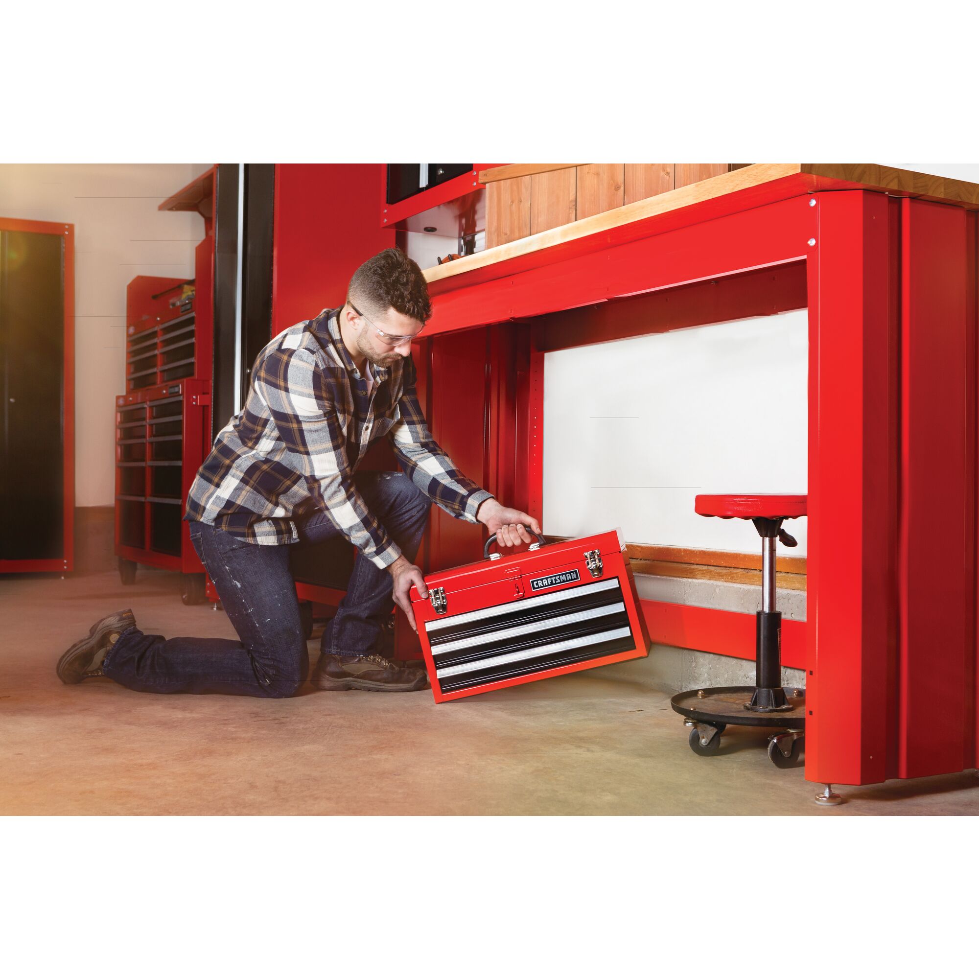Portable 20 and 5 tenths inch Ball bearing 3 Drawer Red Steel Lockable Tool Box being stored by person under workstation.