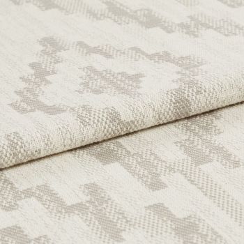 Woven upholstery fabric with light beige geometric motif, folded over once showing textured weave; close-up studio shot with neutral lighting emphasizing fibers and subtle pattern.