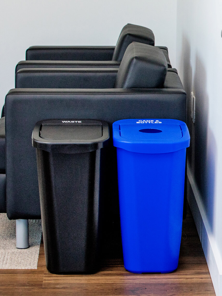 small black and blue plastic waste and recycling bins sitting beside leather chairs in an upscale lawyers office