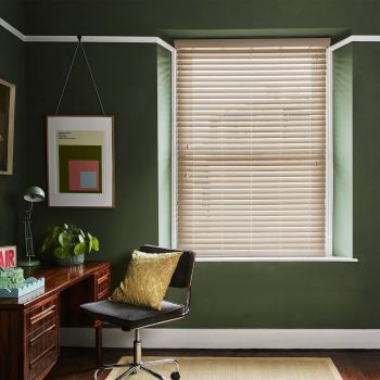 Beige horizontal venetian blinds mounted inside a window recess, slats mostly closed, filtering soft daylight; small dark-green home study with wooden desk, swivel chair and yellow cushion.
AIR