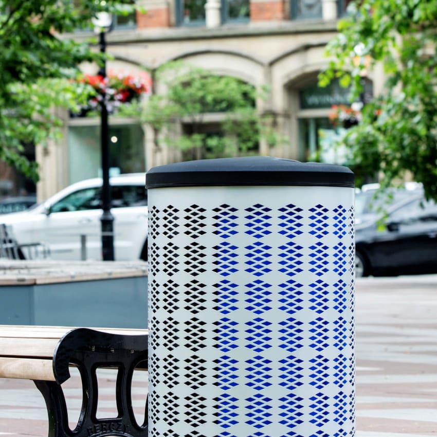 silver powder coated steel recycling bin with a black liner and lid sitting in a town park area