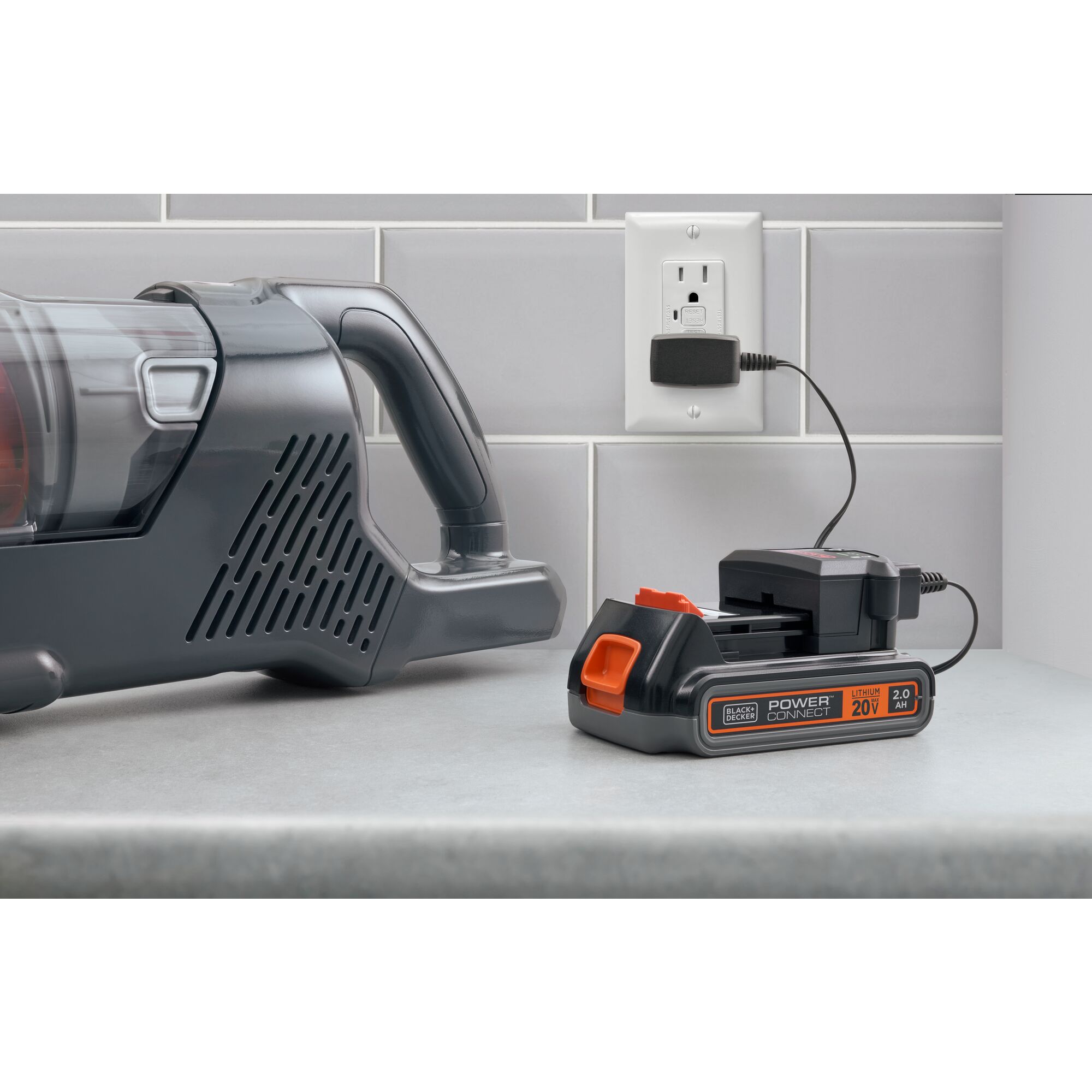 Black and decker 20 volt power series battery connteced to a plugged in charger on a countertop next to a powerseries vacuum